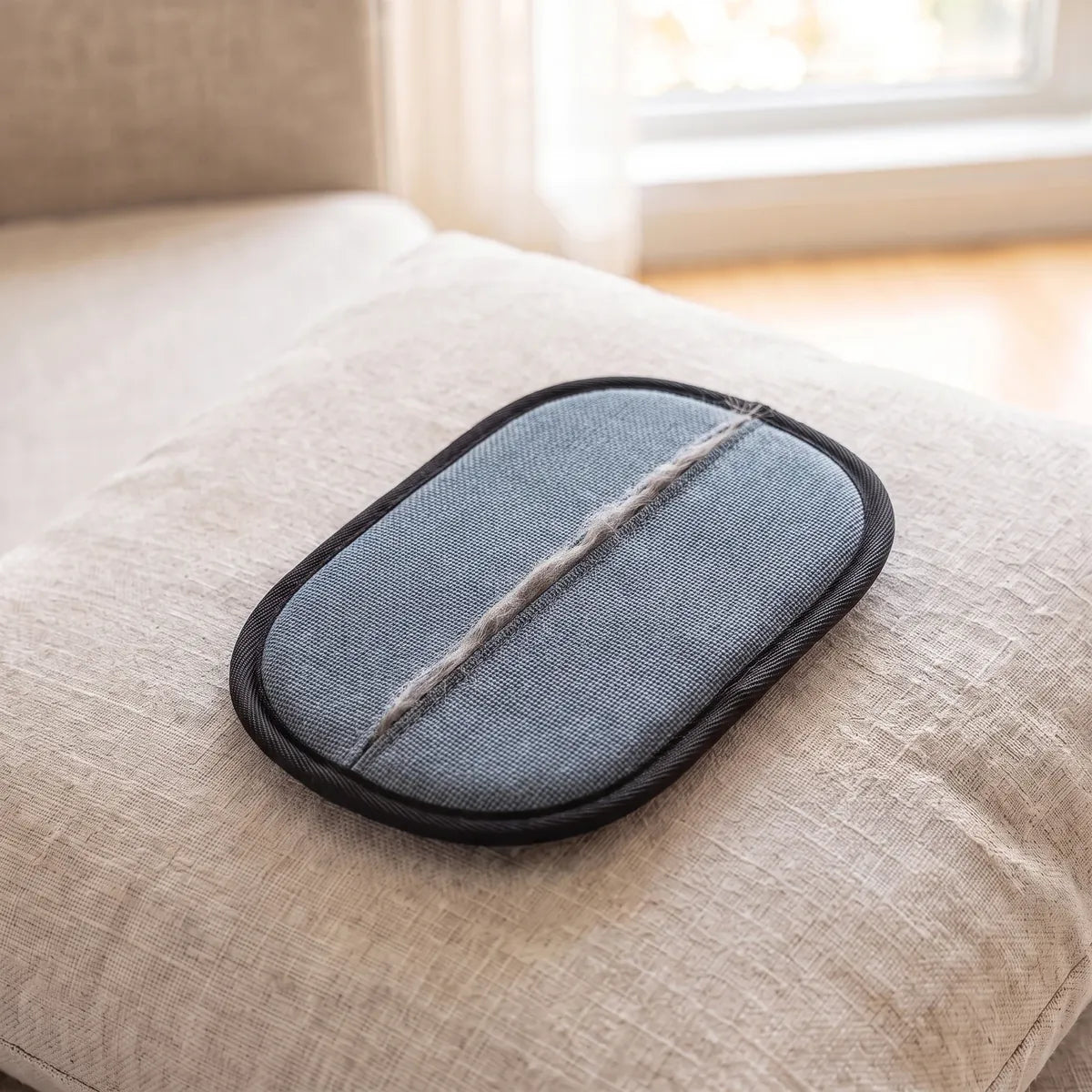 The grey side of the Meto glove with a strip of gathered hair, on a cushion