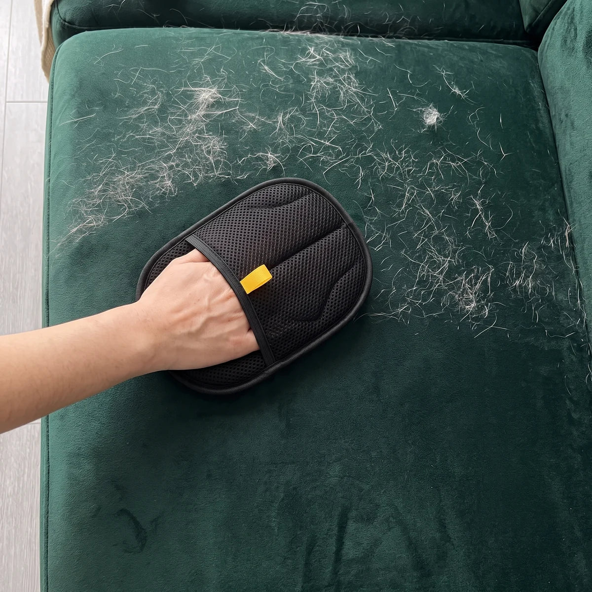 The glove swept over a green velvet sofa covered in hair