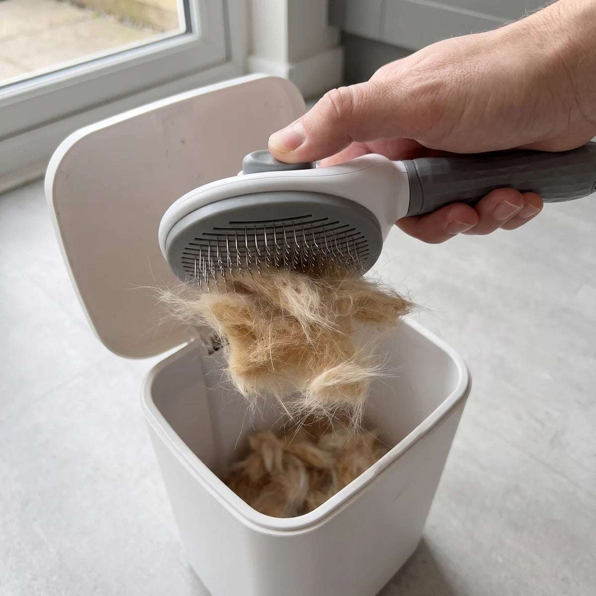 Les poils ramassés glissent de la brosse dans une poubelle